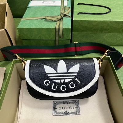 GUCCI古馳 adidas x Gucci聯名系列迷你手袋。adidas和Gucci再啟聯名合作新篇章，繼續以織帶元素和GG字母交織圖案巧妙搭配白色三條紋和三葉草徽標。該系列靈感源自創作總監80年代和90年代的美好回憶，融匯兩個品牌豐富悠